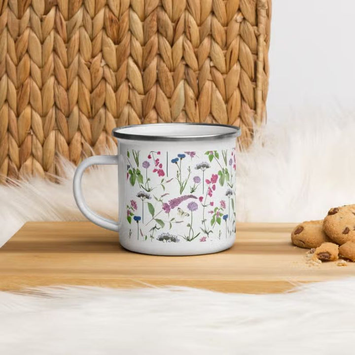 An enamel mug with watercolour-style wildflower design next to cookies