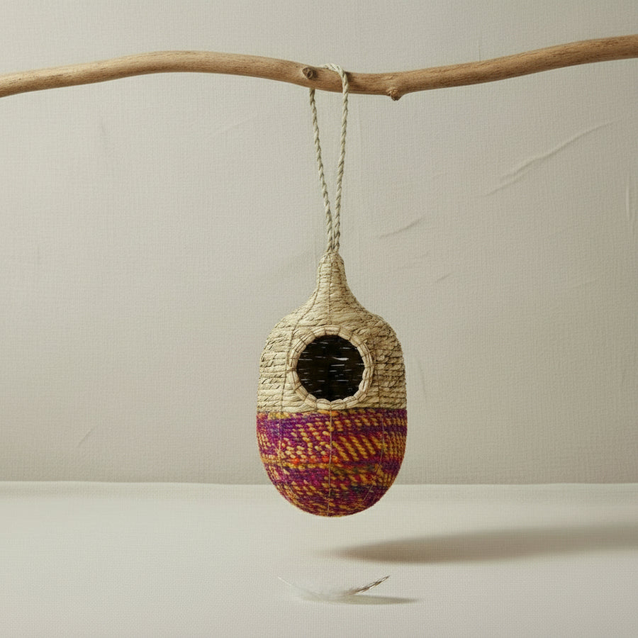 Artisan bird nest with its colourful woven bottom against a white background