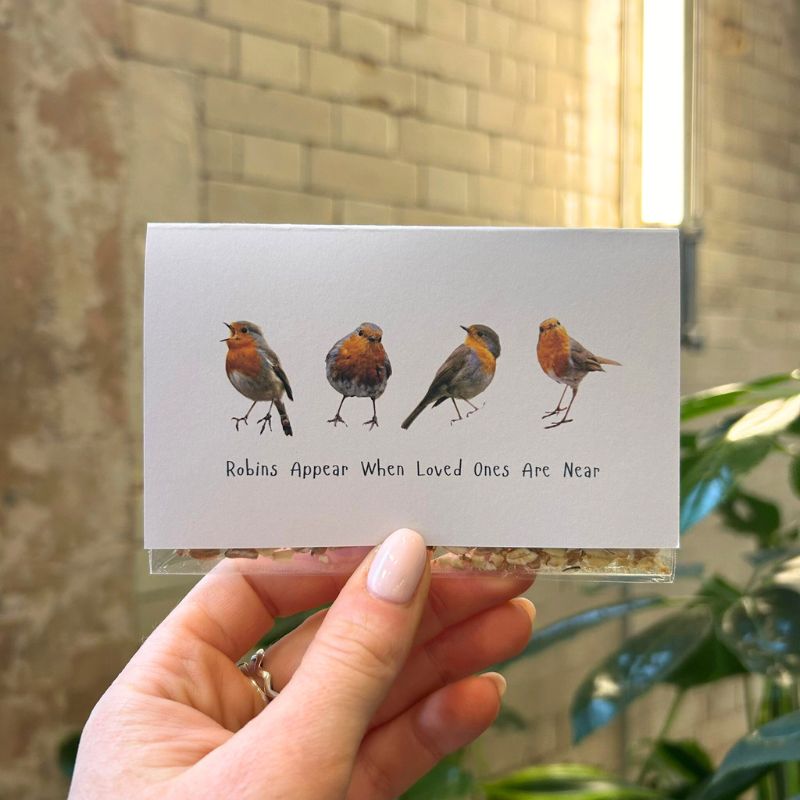 A mini seed packet enclosed within a small white card. 4 robins are on the front of the card with text underneath "Robins Appear When Loved Ones Are Near"