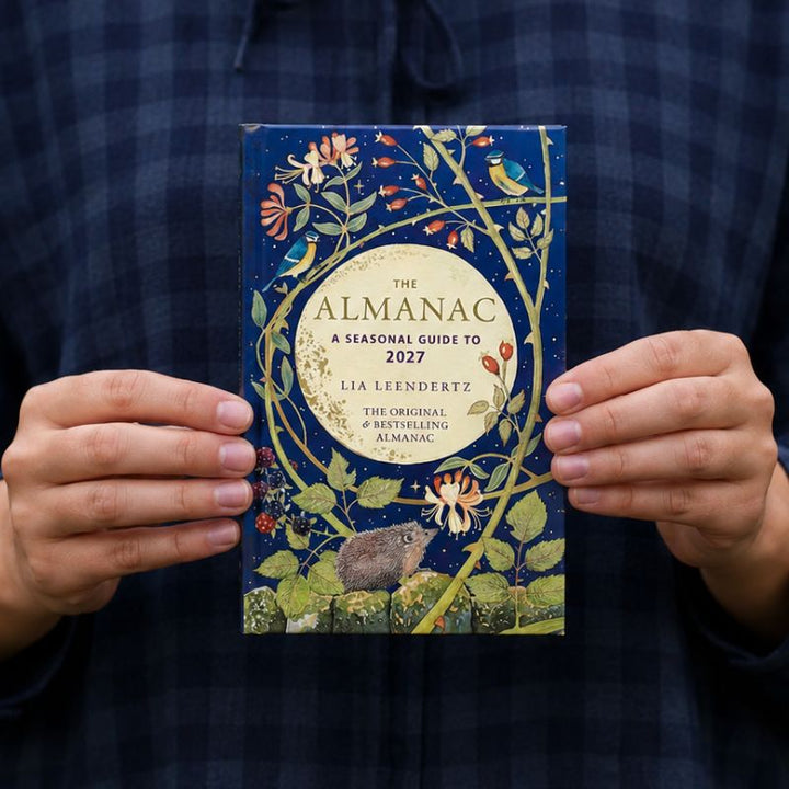 The Almanac book held by a woman in a nvey and blue dress