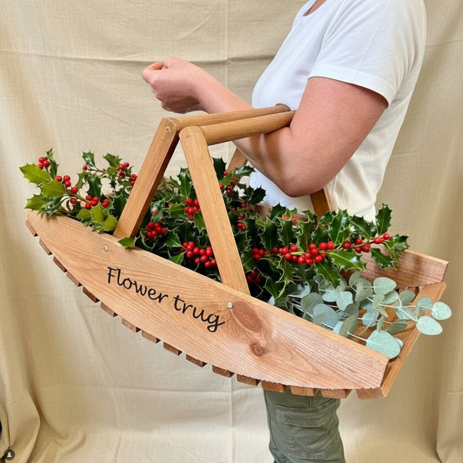 woman hiolding a trug with holly and eucalyptus 