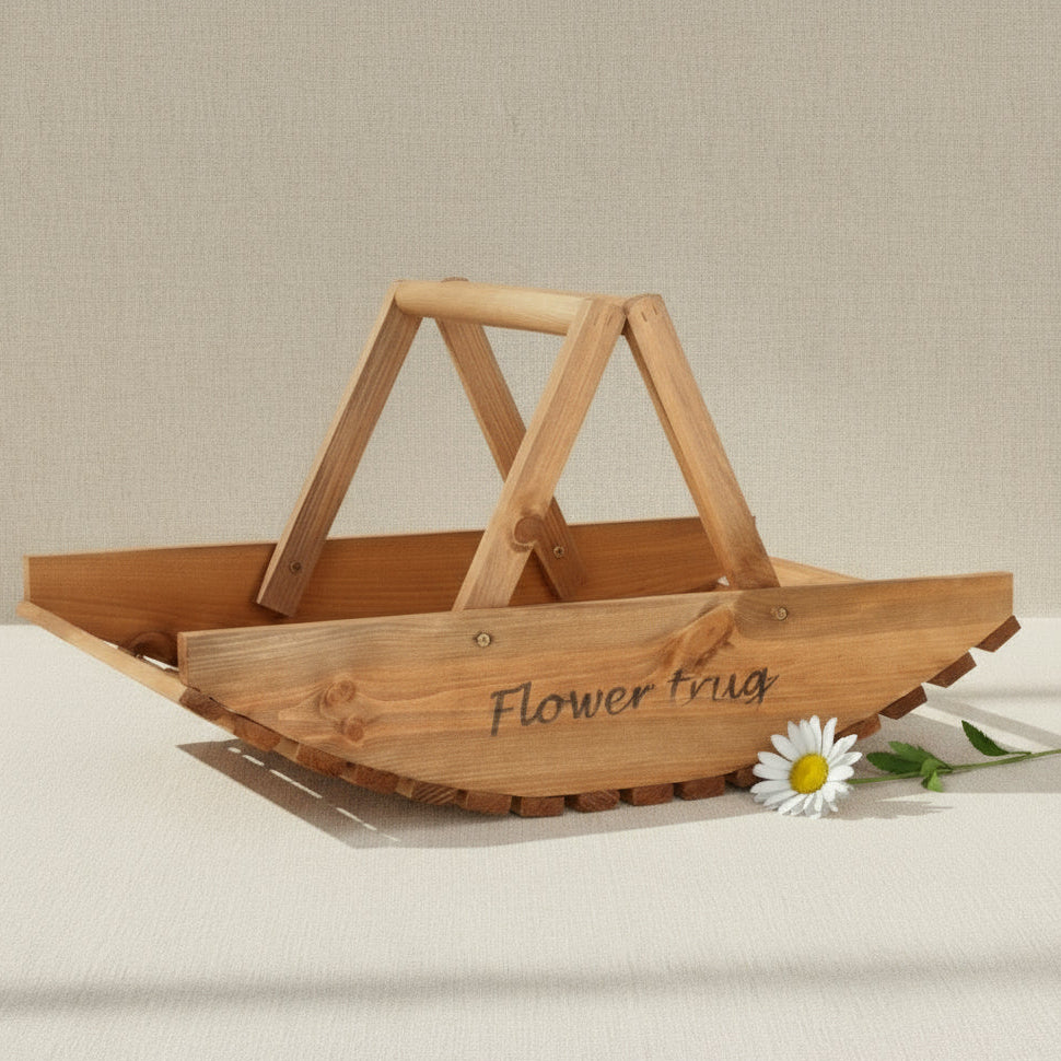 A basket made of solid wood pieces with a curved, slatted wooden base and the words 'Flower trug' in flowy handwriting engraved on the side